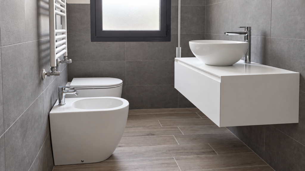 Bagno di Appartamento AV a Padova con lavabo da appoggio, mobile sospeso bianco, sanitari a terra e rivestimenti grigi.